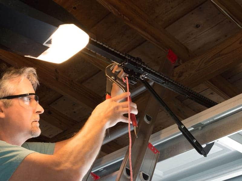 A man working on the chain of a garage door that was recently bought.