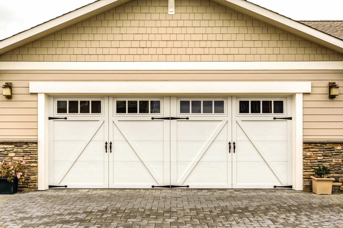 A lightly colored home with a white wood garage door.