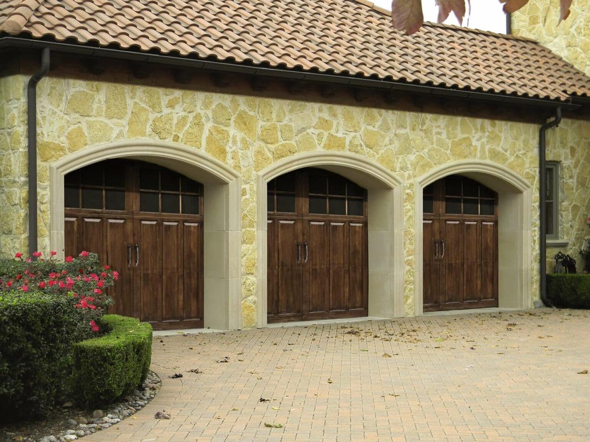 A yellow home with three brown garage doors.